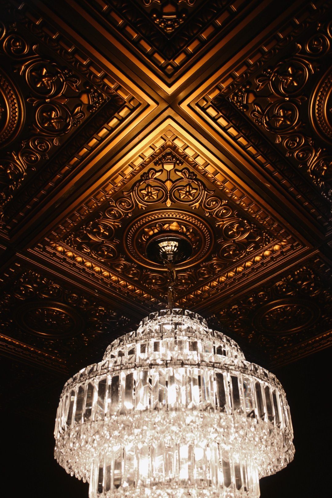 Crystal chandelier against ornate gold ceiling