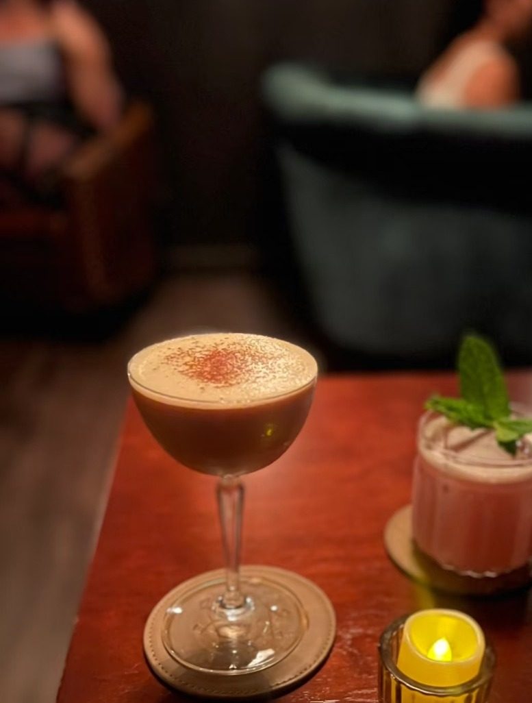 Espresso martini and pink cocktail with mint garnish by candlelight