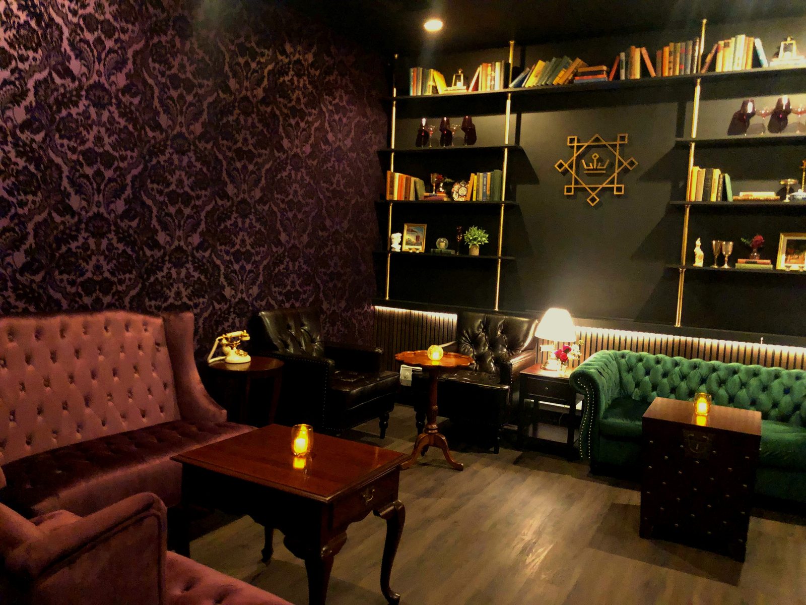 The Library — damask wallpaper, tufted sofas, bookshelves with crown emblem