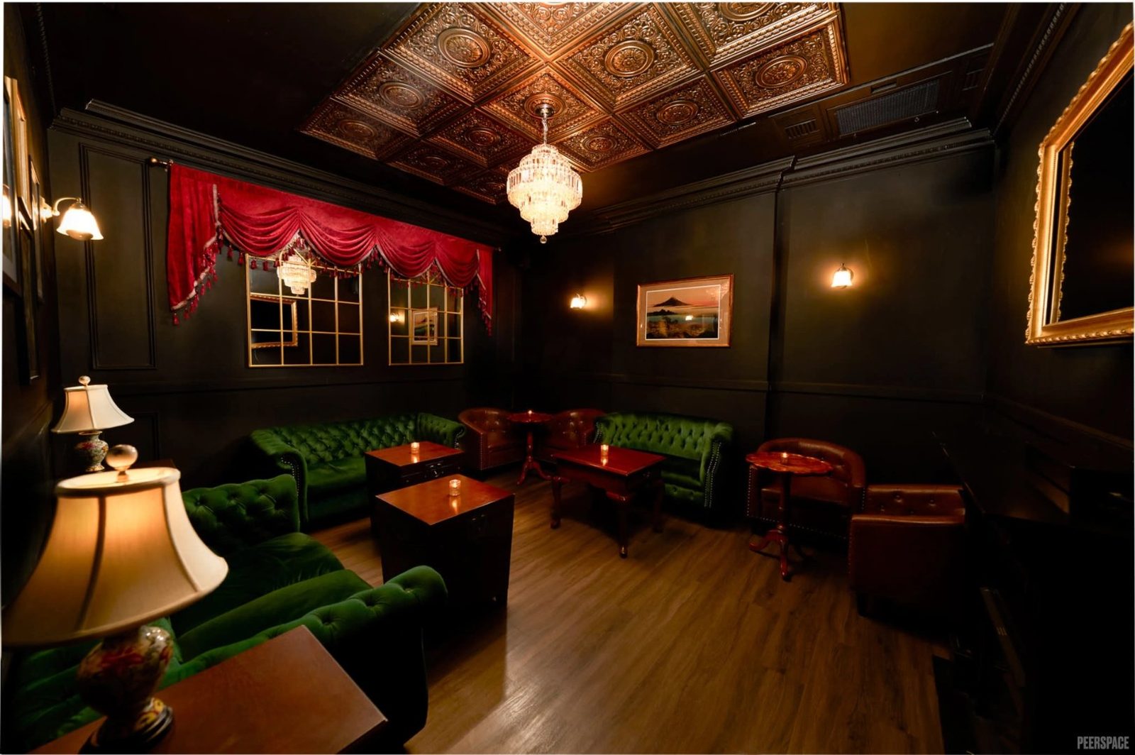 The Lounge — emerald Chesterfield sofas, crystal chandelier, red velvet drapes